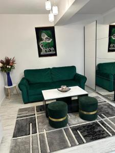 a living room with a green couch and a table at Andra Rezidence in Popeşti-Leordeni