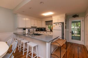 a kitchen with white cabinets and a counter with stools at Miss Irene in Edisto Island