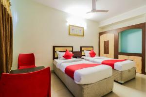 a hotel room with two beds and a red chair at Super Hotel O Parnasala Princely in Rājahmundry +26 photos