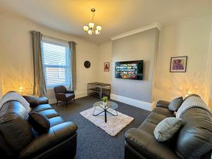 a living room with two leather couches and a television at The Whitley Maisonette, Luxury Family Holiday Home in Whitley Bay