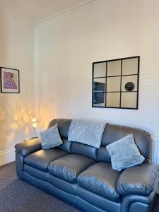 a brown leather couch in a living room at The Whitley Maisonette, Luxury Family Holiday Home in Whitley Bay