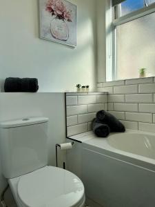 a white bathroom with a toilet and a tub and a sink at The Whitley Maisonette, Luxury Family Holiday Home in Whitley Bay +33 photos