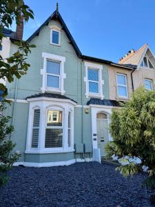 a green house with a white front door at The Whitley Maisonette, Luxury Family Holiday Home in Whitley Bay