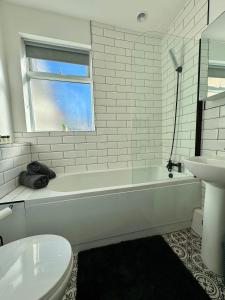 a white bathroom with a tub and a sink at The Whitley Maisonette, Luxury Family Holiday Home in Whitley Bay