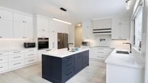 a kitchen with white cabinets and a black island at Modern suite with private bathroom Yonge Finch sub in Bélanger
