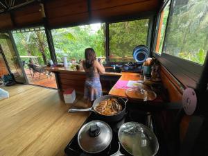 a young girl standing in a kitchen looking out the window at Cabaña Río San Carlos Ecolodge in Boca Tapada