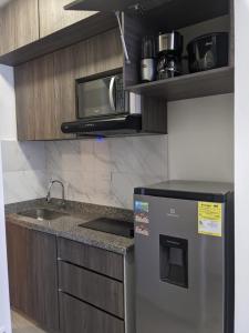 a kitchen with a sink and a microwave and a refrigerator at Encantador apartaestudio Charming studio apartment in Bogotá