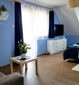 a blue bedroom with a bed and a table with a potted plant at Lilla Vendégház in Balatonudvari +6 photos