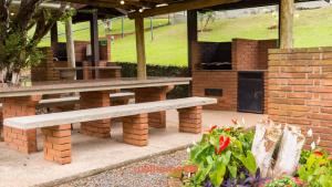 a picnic table and benches in a garden at Flat em Serra Negra com Piscina in Serra Negra