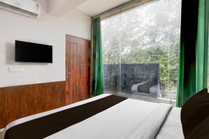 une chambre avec un lit et une grande fenêtre dans l'établissement Hotel O Square Residency, à Rājpur