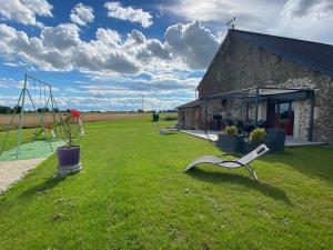 a chair sitting in the grass in front of a building at "Au tour des sens " in La Jumellière +3 photos