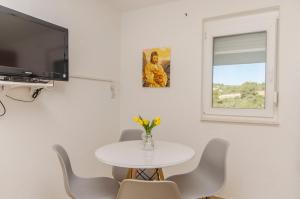 a white dining room with a table and a window at Apartments Nedi in Podglavica
