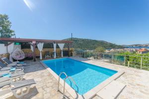 a swimming pool with chaise lounge chairs next to at Apartments Nedi in Podglavica