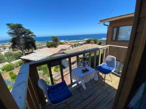 a balcony with a table and two chairs and the ocean at Hostal F in El Quisco