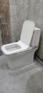 a white toilet in a bathroom with a wall at Chetiya Farmhouse in Paikbara