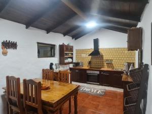a kitchen with a wooden table with chairs and a stove at Casa La Gollada in Cazadores