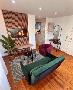 a living room with a green couch and a fireplace at L'Ecrin Alsacien - Proche Europa Park - Idéal Famille & Professionnel - Commerces à Proximité in Erstein