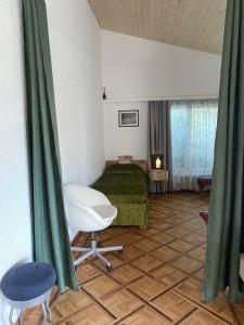 une chambre avec un lit et des rideaux verts et une chaise dans l'établissement Duplex Loft Apartment, à Evilard