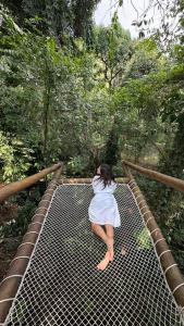a woman in a white dress laying on a metal bridge at Casa Natu Ilhabela Portinho in Ilhabela