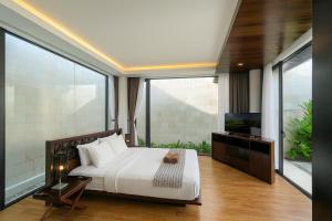 a bedroom with a white bed and a television at Akhyana Village in Jimbaran