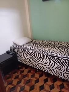a bed with a black and white comforter on it at Club La Riviera in Ipiales