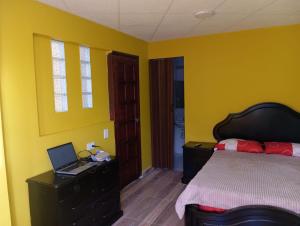 a bedroom with a bed and a laptop on a desk at Club La Riviera in Ipiales