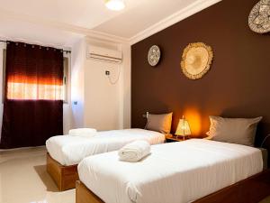 um quarto com duas camas com lençóis brancos em Fib Houses em Ouarzazate