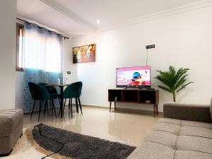 uma sala de estar com televisão e mesa com cadeiras em Fib Houses em Ouarzazate