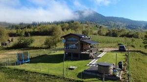 a house in a field with a mountain in the background at Recele Tiny Nest in Ilva Mare