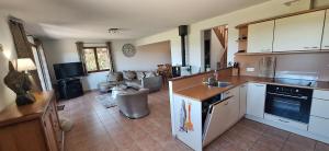 a kitchen with white cabinets and a living room at Résidence Hirondelle Corrèze in Saint-Salvadour