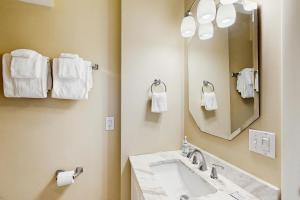 a bathroom with a sink and a mirror and towels at Oceanfront Townhouse in Carolina Beach +21 photos