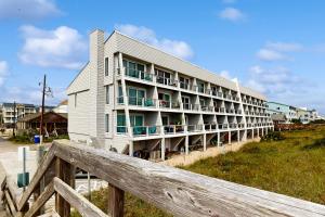 a building on the beach with a wooden fence at Oceanfront Townhouse in Carolina Beach