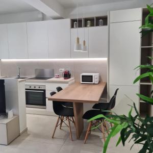 a white kitchen with a wooden table and chairs at RESIDENZA CORSO DALMAZIA in Civitanova Marche