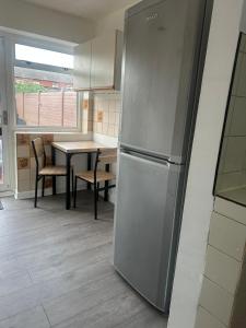 Una cocina con refrigerador de acero inoxidable y una mesa. en Clayburn Circle Cosy Stay, en Basildon