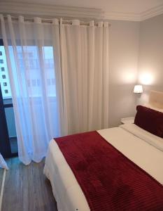a bedroom with a bed and a large window at Oscar Freire Confort in Sao Paulo
