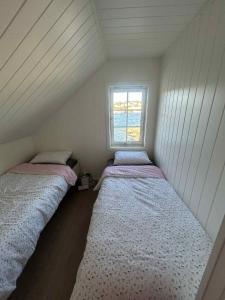 two beds in a small room with a window at Hytte med sjøen in Kristiansand