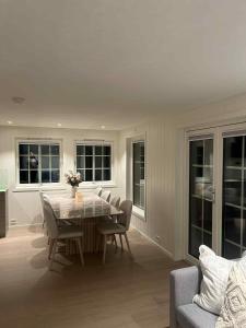 a dining room with a table and chairs and windows at Hytte med sjøen in Kristiansand