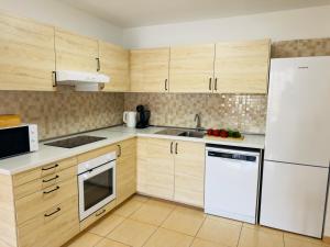 a kitchen with wooden cabinets and a white refrigerator at Bright Retreat with Lush Outdoor Space in Palm-Mar
