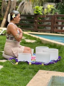 a woman sitting on the grass next to a pool at Posada Sian Kaan Playa del Carmen - Wellness Oriented Hotel in Playa del Carmen