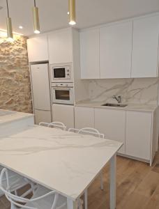 a kitchen with white cabinets and a white table at La Casa del Campanar in Traiguera +25 photos