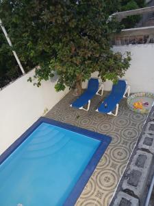 a blue swimming pool next to two chairs and a tree at Villa en Boca chica in Boca Chica +9 photos