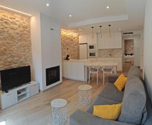 a living room with a couch and a tv and a kitchen at La Casa del Campanar in Traiguera