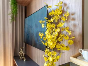 a vase with yellow flowers in front of a tv at Apartamento sofisticado c vaga e vista Arena MRV in Belo Horizonte
