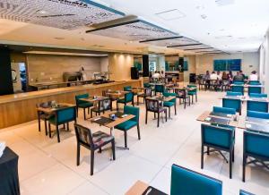 a restaurant with tables and chairs and a bar at Apto Studio novo, a passos da Praia com lazer completo in Santos