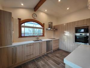 a kitchen with wooden cabinets and a sink and a window at Heritage & Heart by the Park in Invercargill