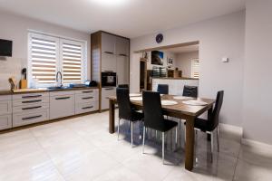 a kitchen with a wooden table and black chairs at Apartament nr 1 Chorzelów in Mielec