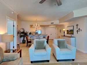 a living room with blue chairs and a kitchen at Portofino Island Resort #2-1002 in Pensacola Beach