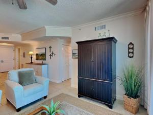 a living room with a blue chair and a cabinet at Portofino Island Resort #2-1002 in Pensacola Beach +30 photos
