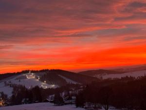 Una puesta de sol en las montañas con un cielo rojo. en Apartmán Schwaderbach, en Bublava