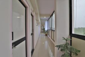 ein leerer Flur mit einer Topfpflanze und einem Fenster in der Unterkunft Hotel O D K Guest House in Anand